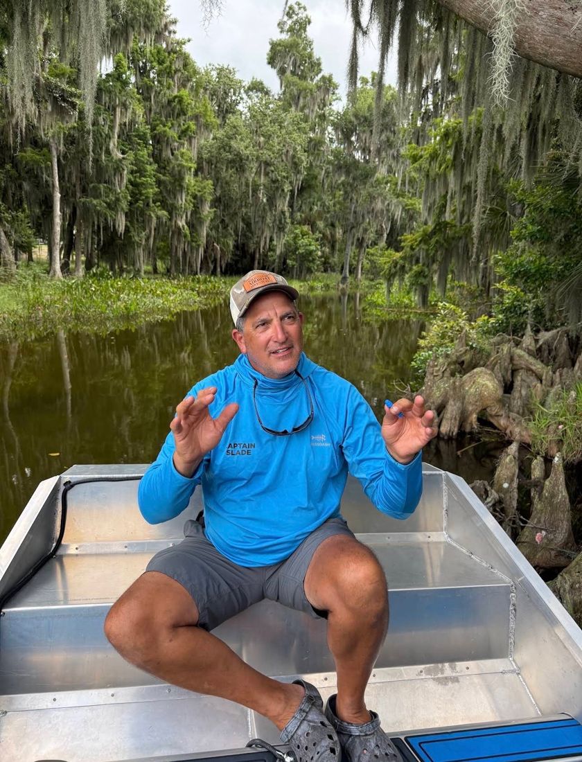 Captain Slade talking to guests from the airboat, under Spanish moss and cypress