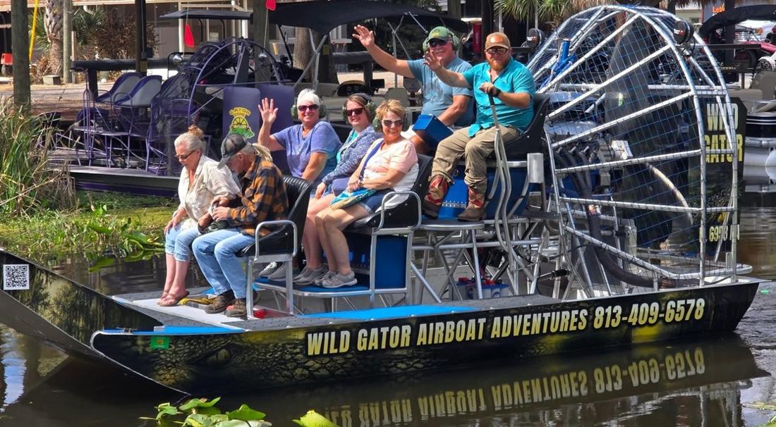Guests waving from the airboat at the dock